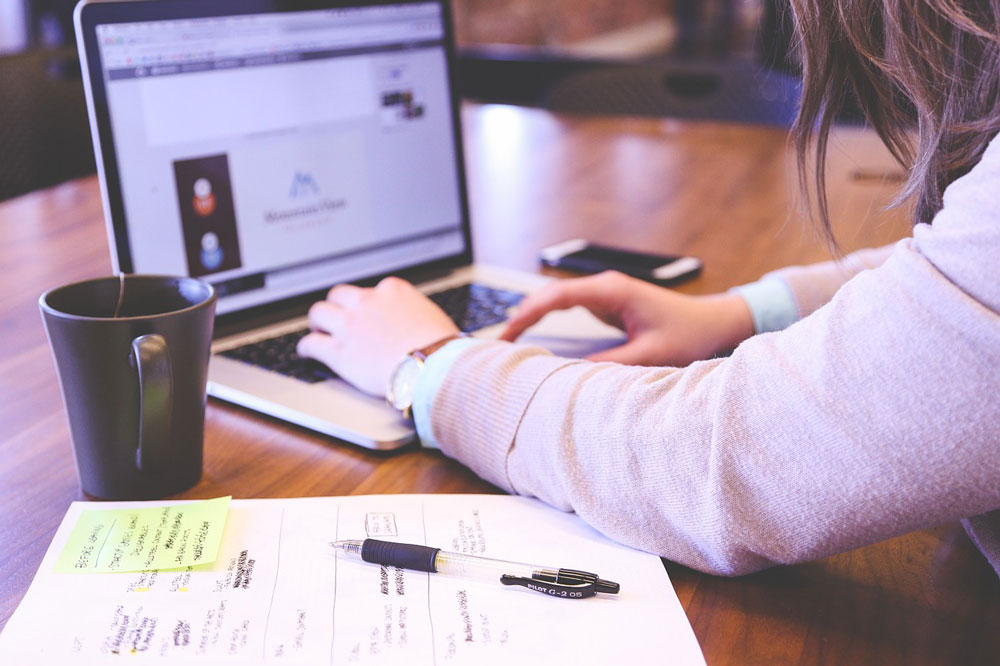 Women typing at computer while doing work.